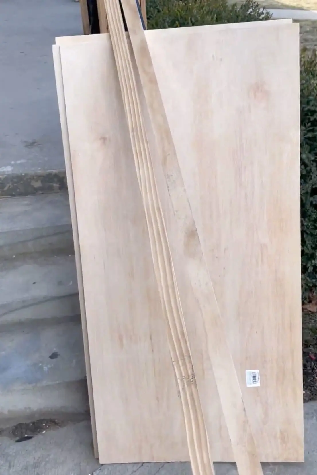 A stack of plywood and wood trim pieces ready to be cut and used for a DIY closet shelving transformation.